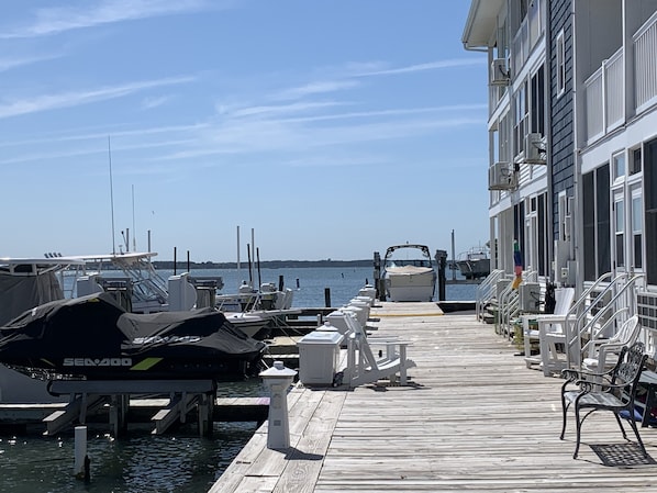 A marina with boats docked, a wooden pier, and a building with balconies.