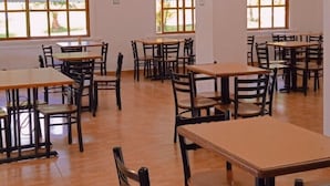 A spacious dining area with multiple tables and chairs, large windows with views, and a chandelier.