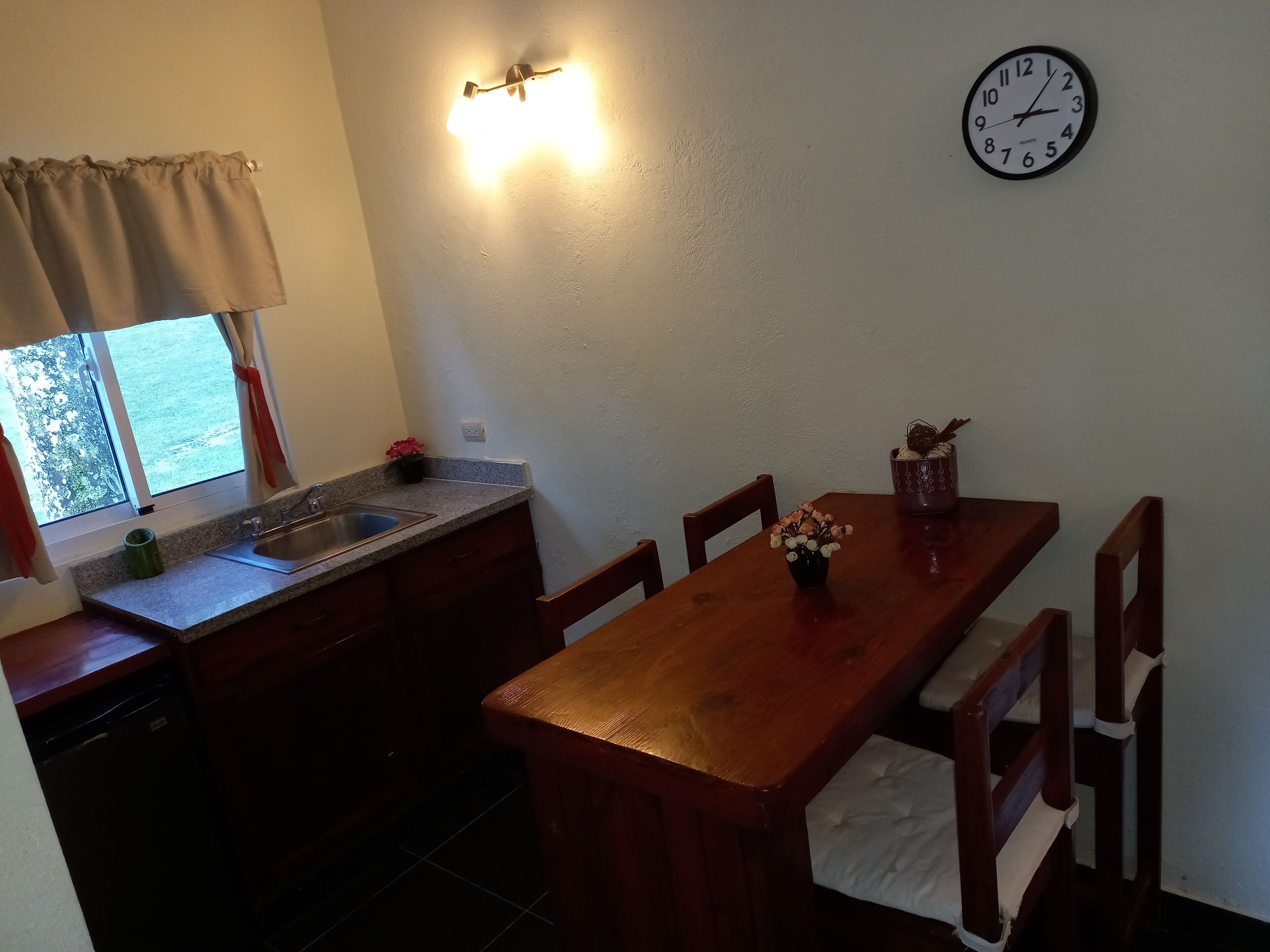 Eine kleine Küche mit Holztisch, Spüle und einer Uhr an der Wand.