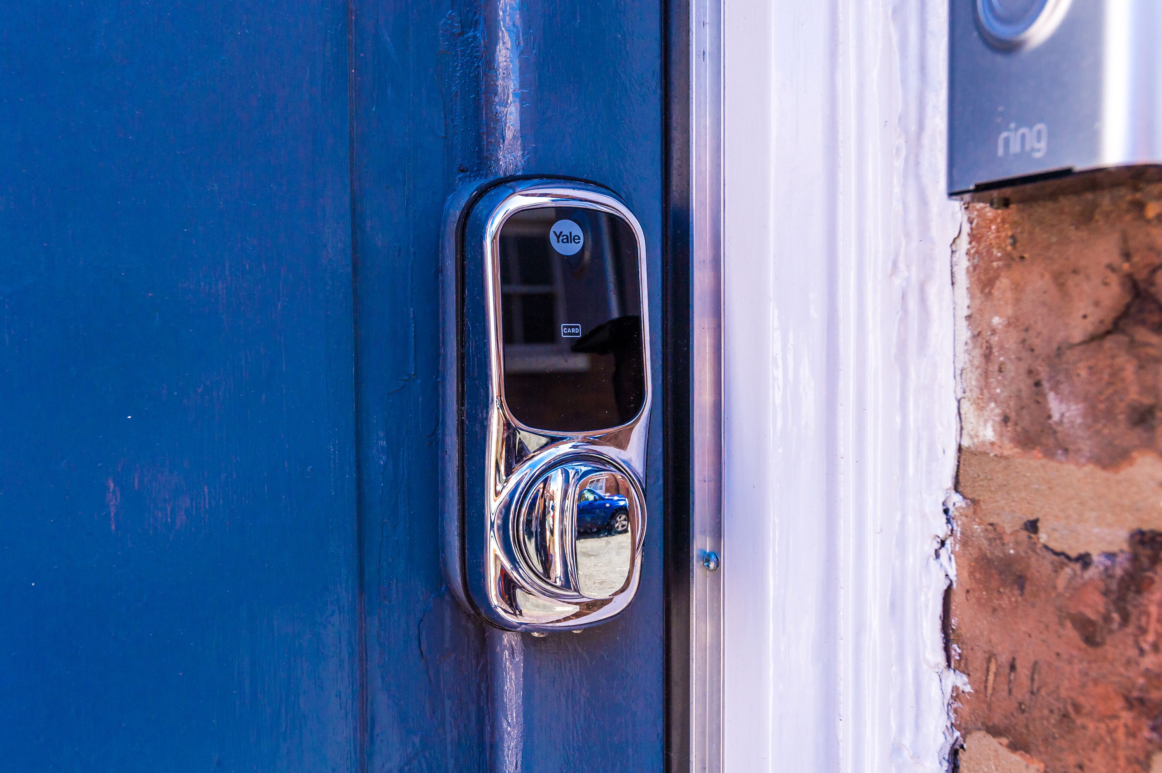 Una puerta azul con un cerrojo Yale y un lector de tarjetas.