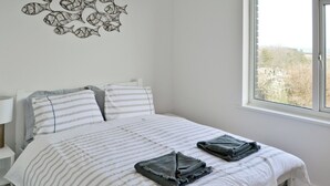 A bedroom with a bed, pillows, a wall art piece, and a window.