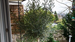 A balcony with potted plants and a view of a garden. - Apartment Oasis - Gemütliche Wohnung mit Garten (Mendig)