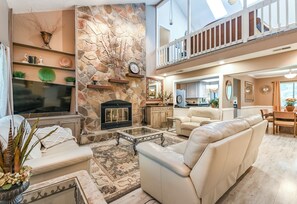 A spacious living area with a stone fireplace, a flat-screen TV, and a comfortable seating arrangement. - Exquisite Summerville Retreat-Walk to Downtown, Festivals & Southern Hospitality (Summerville)