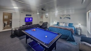 A room with a pool table, a bed, a television, and a ceiling fan. - Exquisite Summerville Retreat-Walk to Downtown, Festivals & Southern Hospitality (Summerville)
