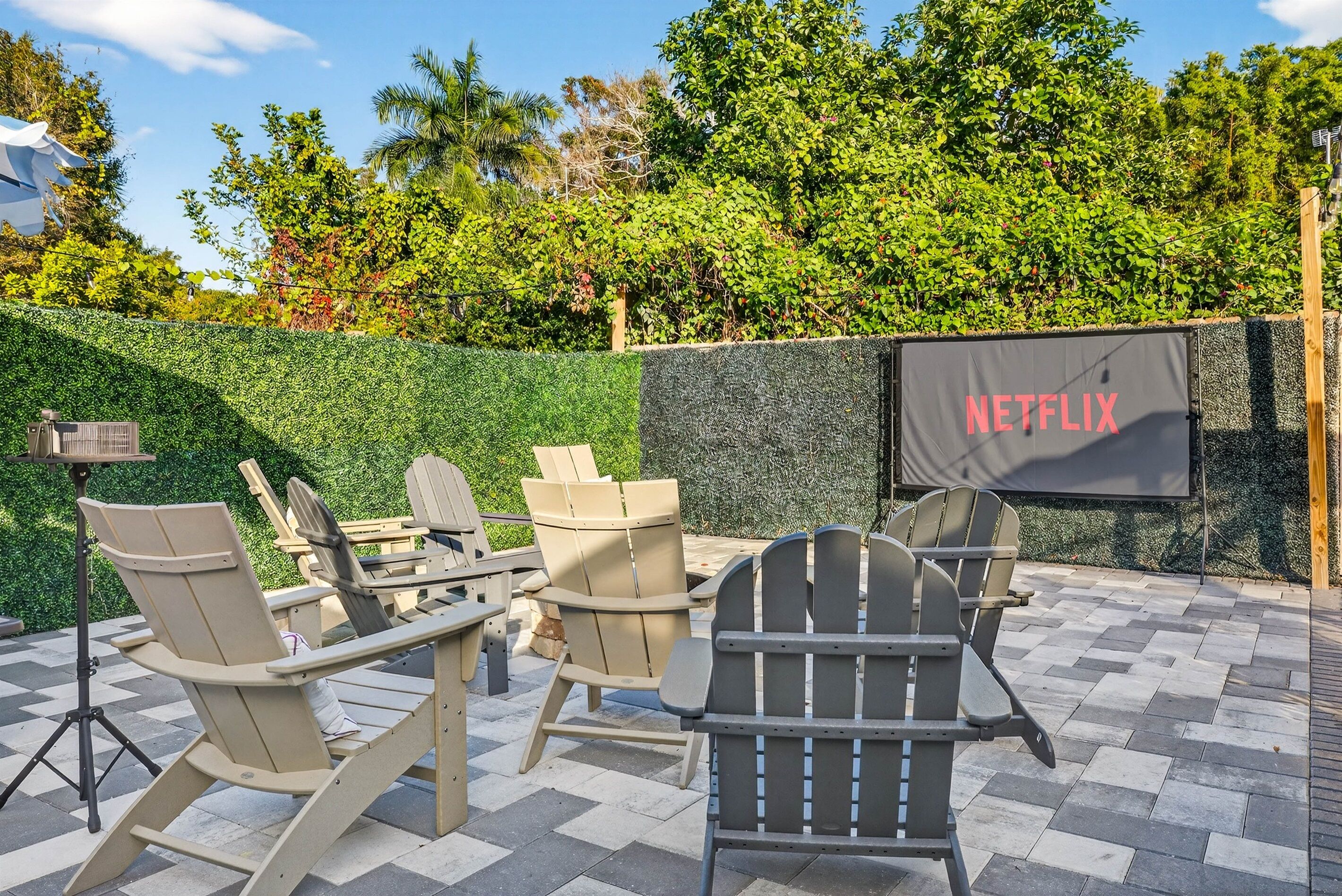 Een buitenzitgedeelte met Adirondack-stoelen en een Netflix-scherm.