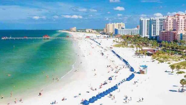 A beach with a pier extending into the ocean, surrounded by high-rise hotels and palm trees. - Paradise Oasis Heated Pool+Hot Tub+Games & Arcade (Largo)