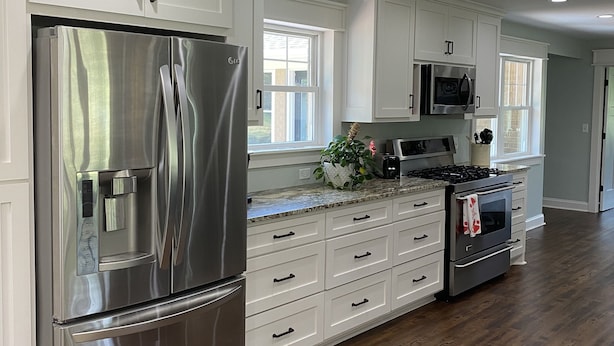 Una cocina moderna con armarios blancos, electrodomésticos de acero inoxidable y piso de madera.