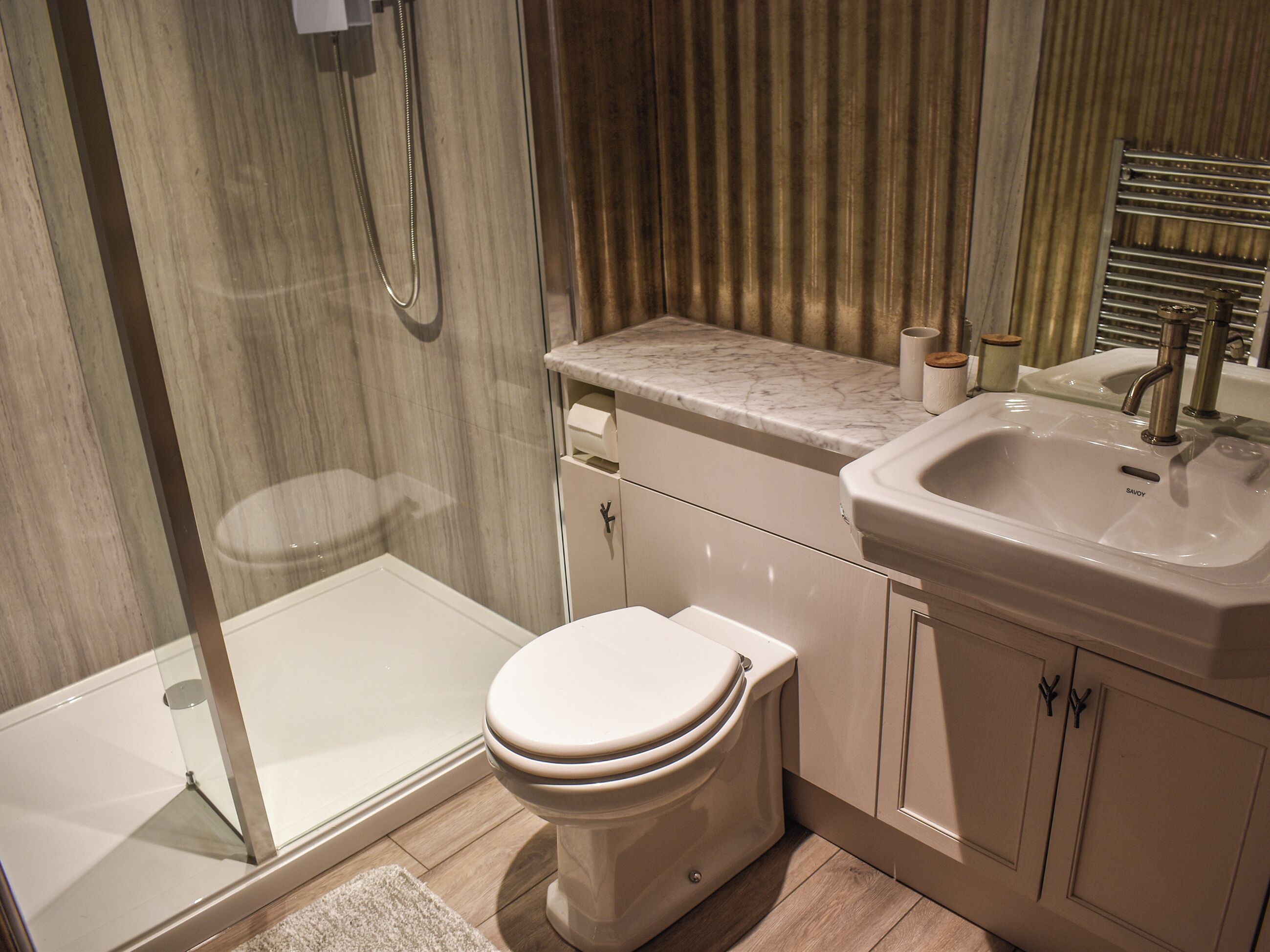 A modern bathroom with a shower, toilet, sink, and marble countertop.