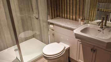A modern bathroom with a shower, toilet, sink, and marble countertop.