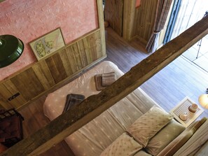 Ein Zimmer mit einem Bett, Holzboden, einer rosafarbenen Wand und einem Fenster.