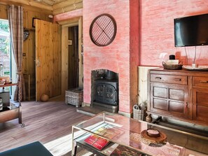 Um quarto acolhedor com porta de madeira, lareira, televisão e mesa de vidro com revistas.