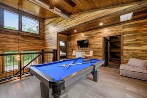Relax in this inviting space with a pool table, comfortable sofa, and balcony offering a view of the outdoors.