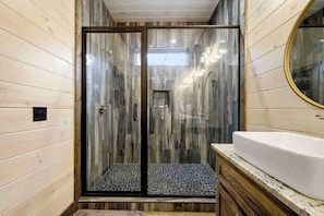 Enjoy a refreshing shower in this bathroom with a glass-enclosed shower area and a large mirror above a sink.