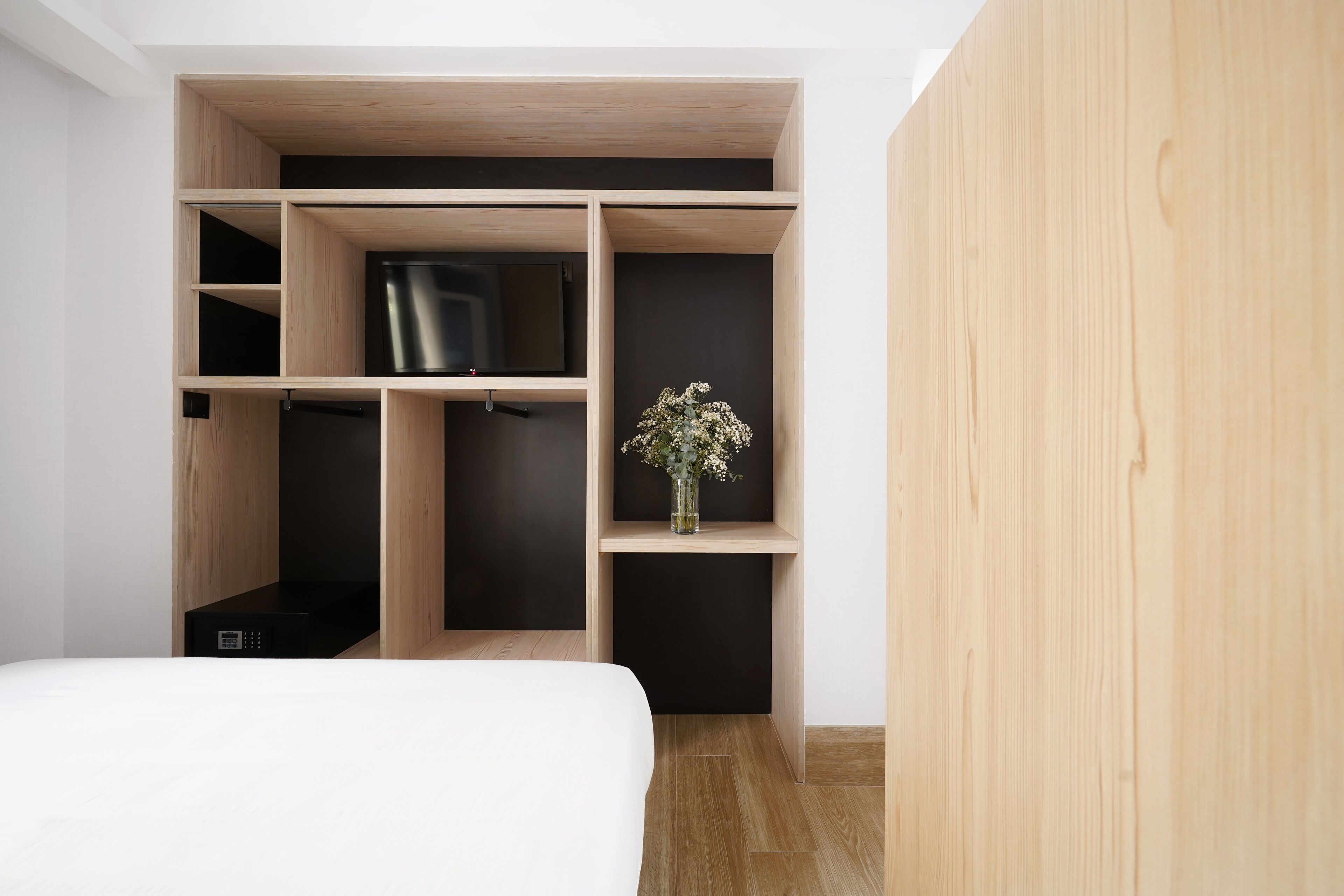 Ein Schlafzimmer mit einem Bett, einem Einbauschrank, einem Fernseher und einer kleinen Pflanze.