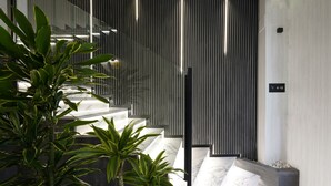 Een modern interieur met een marmeren trap, verticale lichtstroken en groene planten.