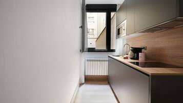 Una cocina estrecha con encimera de madera, horno empotrado y vistas al exterior a través de una ventana.