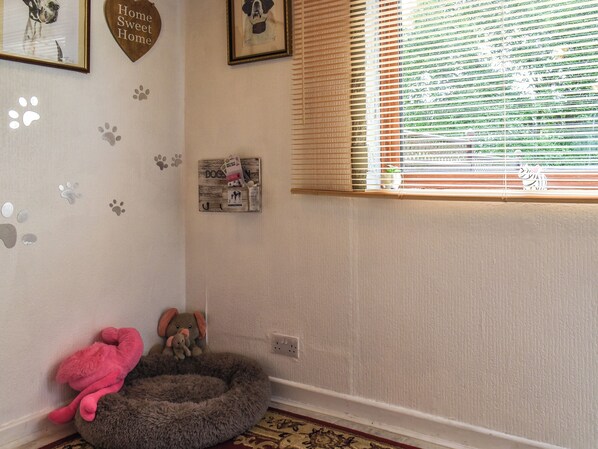 Une pièce avec un panier pour animal de compagnie, un tableau encadré et un mur décoré d’empreintes de pattes.