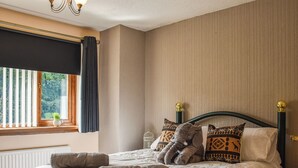 Un lit bien fait, avec des oreillers et une couverture, une fenêtre avec des rideaux et un radiateur.