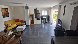 Una sala moderna con un sofá, una mesa de comedor, una zona de cocina y un televisor.