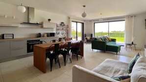 Una cocina moderna con comedor, un sofá verde y vistas al exterior.