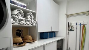 Un cuarto de lavado con lavadora, toallas dobladas con orden, un sombrero y productos de limpieza.