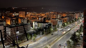 Une vue nocturne d'une ville, avec des bâtiments illuminés et une rue animée.