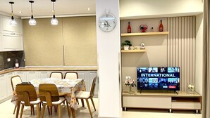 Une cuisine moderne avec un coin repas, une horloge et un téléviseur affichant le mot « INTERNATIONAL ».