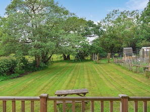 A grassy field with a wooden bench and a fence.