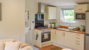Een kleine keuken met een fornuis, oven, magnetron en spoelbak.