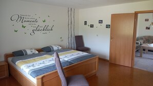 A bedroom with a bed, a chair, a wardrobe, and a door. - Vacation apartment in a quiet, rural location (Großefehn)