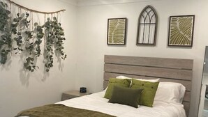 Une chambre à coucher avec un lit, un ventilateur de plafond et des œuvres d’art murales.