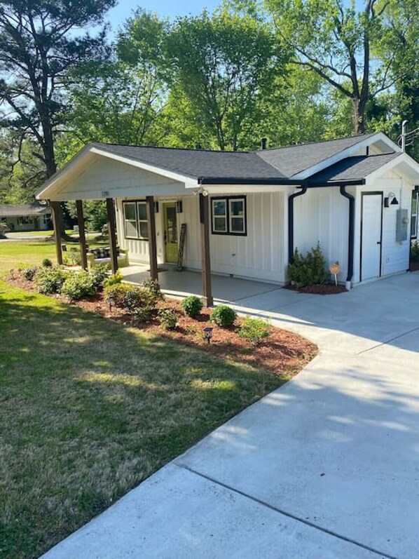 Ein eingeschossiges Haus mit überdachter Veranda, Garage und gepflegtem Rasen.