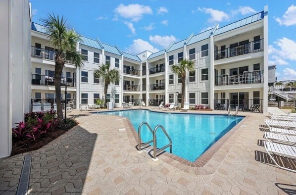 A hotel with a swimming pool, multiple balconies, and palm trees. - Direct Beach Access - Top Floor Unit - Gulf Views From Complex. (Destin)