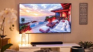 Televisor de pantalla plana montado en la pared mostrando una vista del atardecer sobre un área de piscina con sillas de descanso y un edificio de techo rojo.