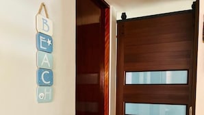 Un pasillo con una puerta de madera y un adorno en la pared que deletrea un nombre.