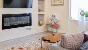 Un salon moderne doté d’un téléviseur à écran plat, d’une cheminée, d’un canapé et d’une table basse.