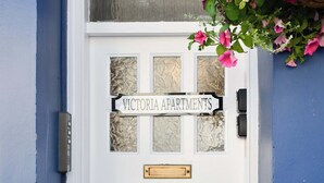 Une porte blanche avec une plaque indiquant « Victoria Apartments » et une fente en laiton pour le courrier.