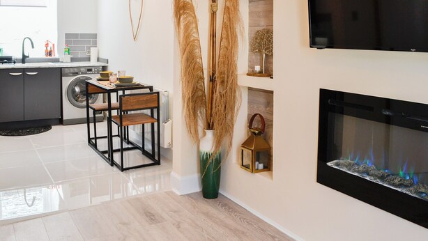 Une cuisine moderne avec un coin repas, une cheminée et un téléviseur fixé au mur.