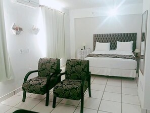 A hotel room with a bed, two chairs, a bedside table, and a mirror. - SAINT JAMES PALACE HOTEL (Lencois Paulista)