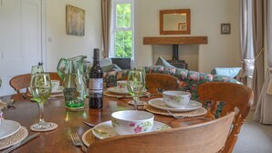 Ein Essbereich mit einem Holztisch, der für eine Mahlzeit gedeckt ist, einer Weinflasche und Geschirr mit floralem Muster.