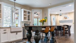 Una cocina con una isla central, muebles blancos y un comedor con sillas y mesa.