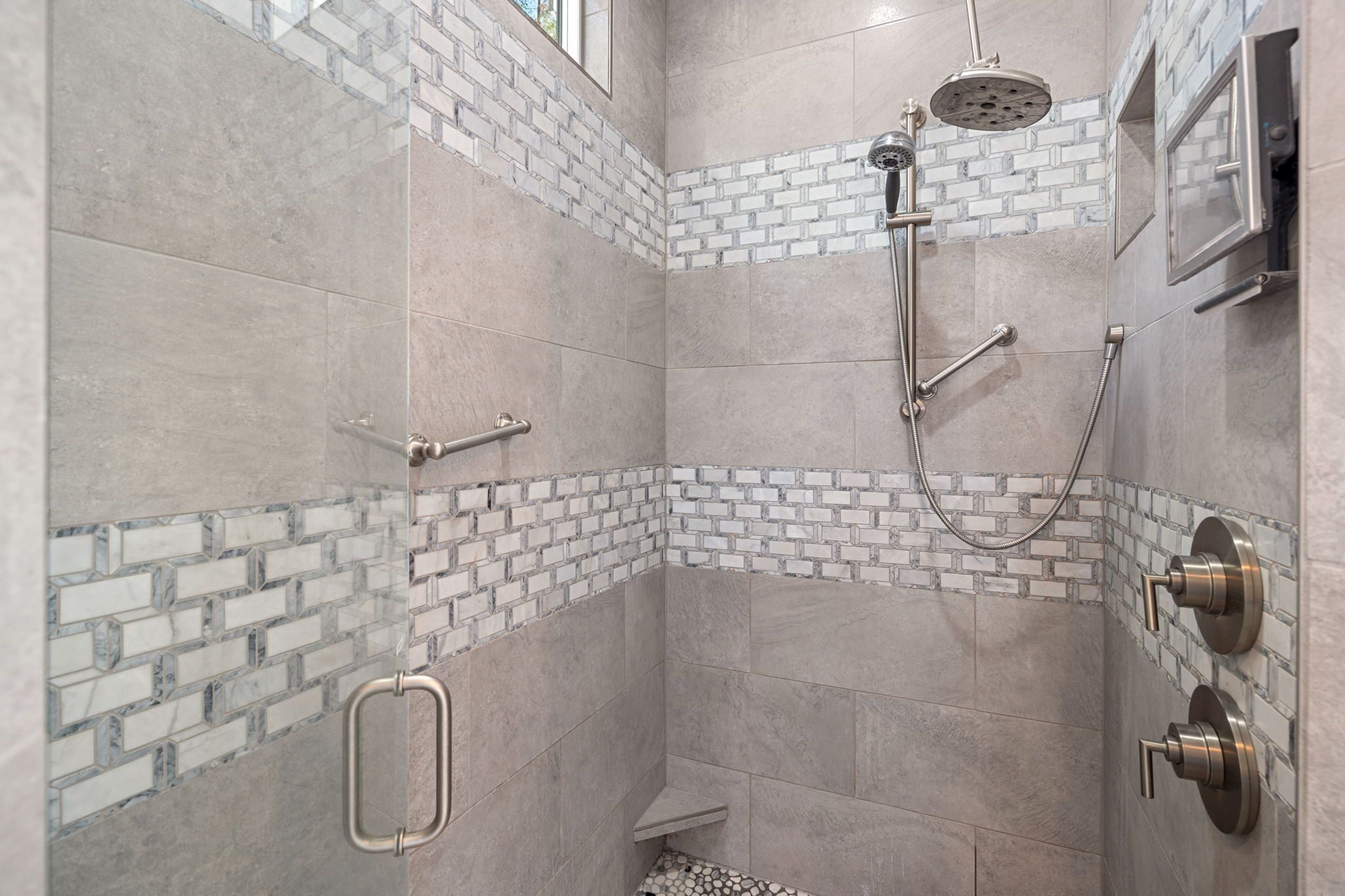 A shower area with a glass block accent wall, a handheld showerhead, and a wall-mounted faucet.