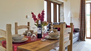 A dining table set with plates, bowls, wine glasses, and a bottle of wine. There is a vase with flowers and a lamp on the table.