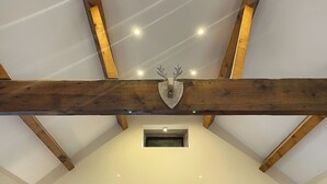 A room with exposed wooden beams, a mounted deer head, and recessed lighting.