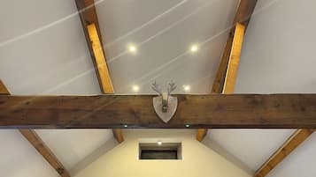 A room with exposed wooden beams, a mounted deer head, and recessed lighting.