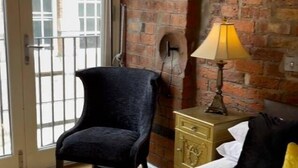 A room with a bed, a chair, a lamp, and a brick wall. - Contractor Mid week bookers (Liverpool)