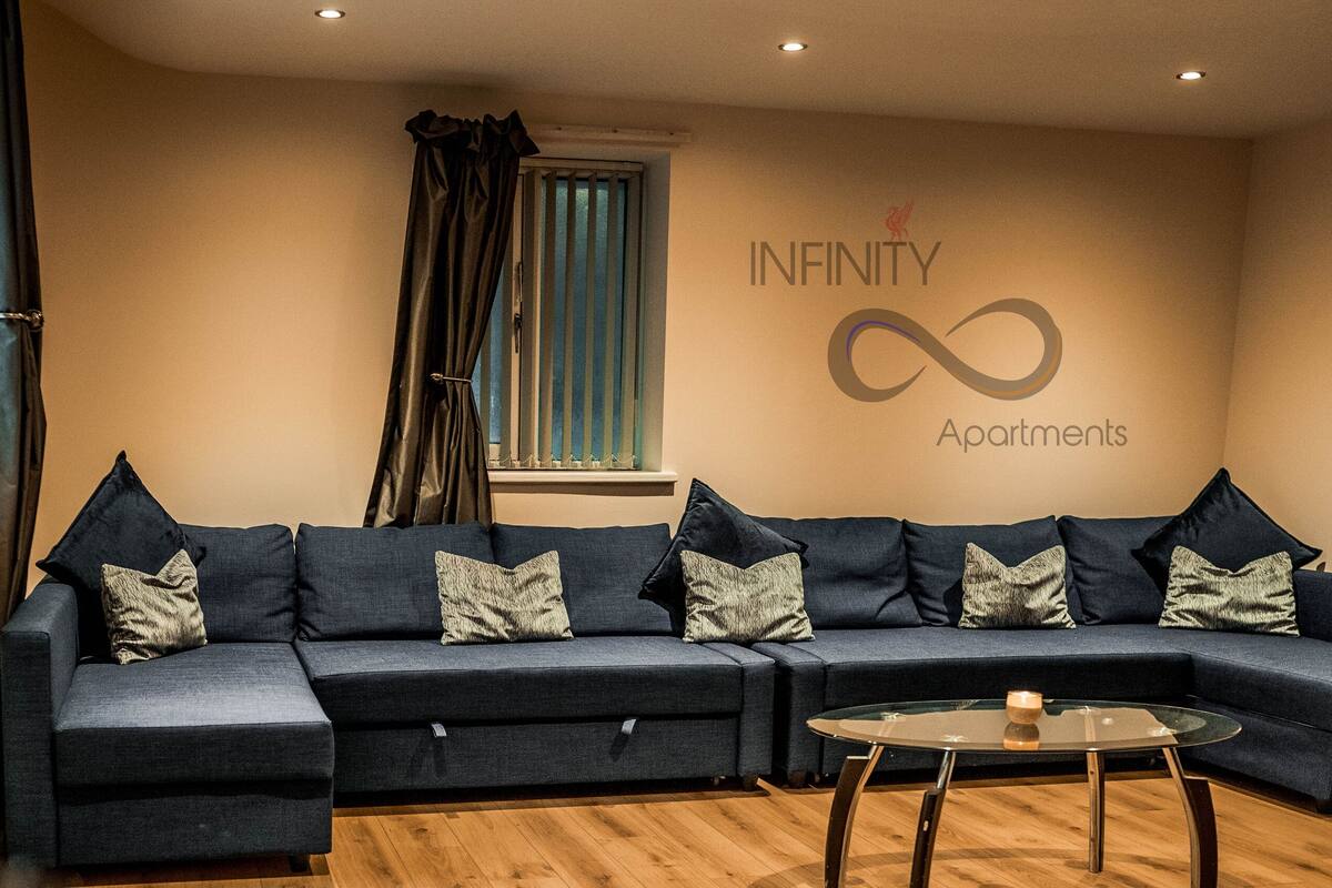 A modern living room with a sectional sofa, a glass coffee table, and a wall-mounted TV.