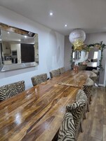 Un comedor con una larga mesa de madera, sillas con estampado de cebra, un espejo grande y una alegre decoración con globos.