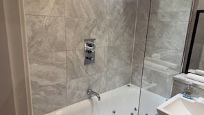 Een moderne badkamer met een bad, een douche en een wastafel.