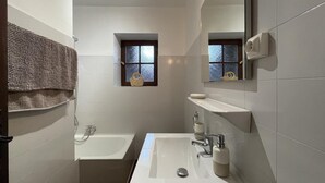 Un baño moderno con bañera, lavabo y ventana.